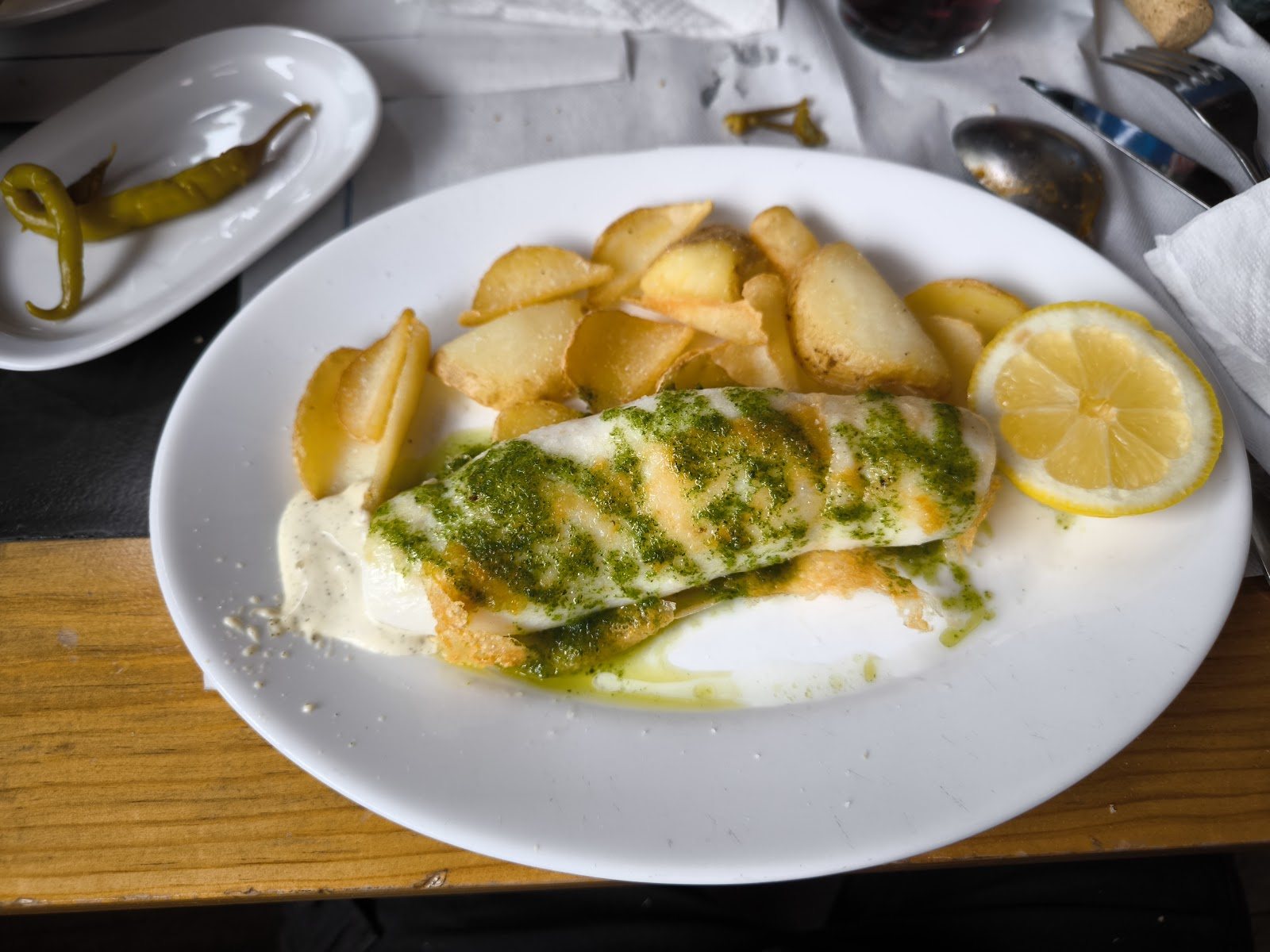 Plato de merluza a la plancha con salsa verde casera y patatas panaderas.